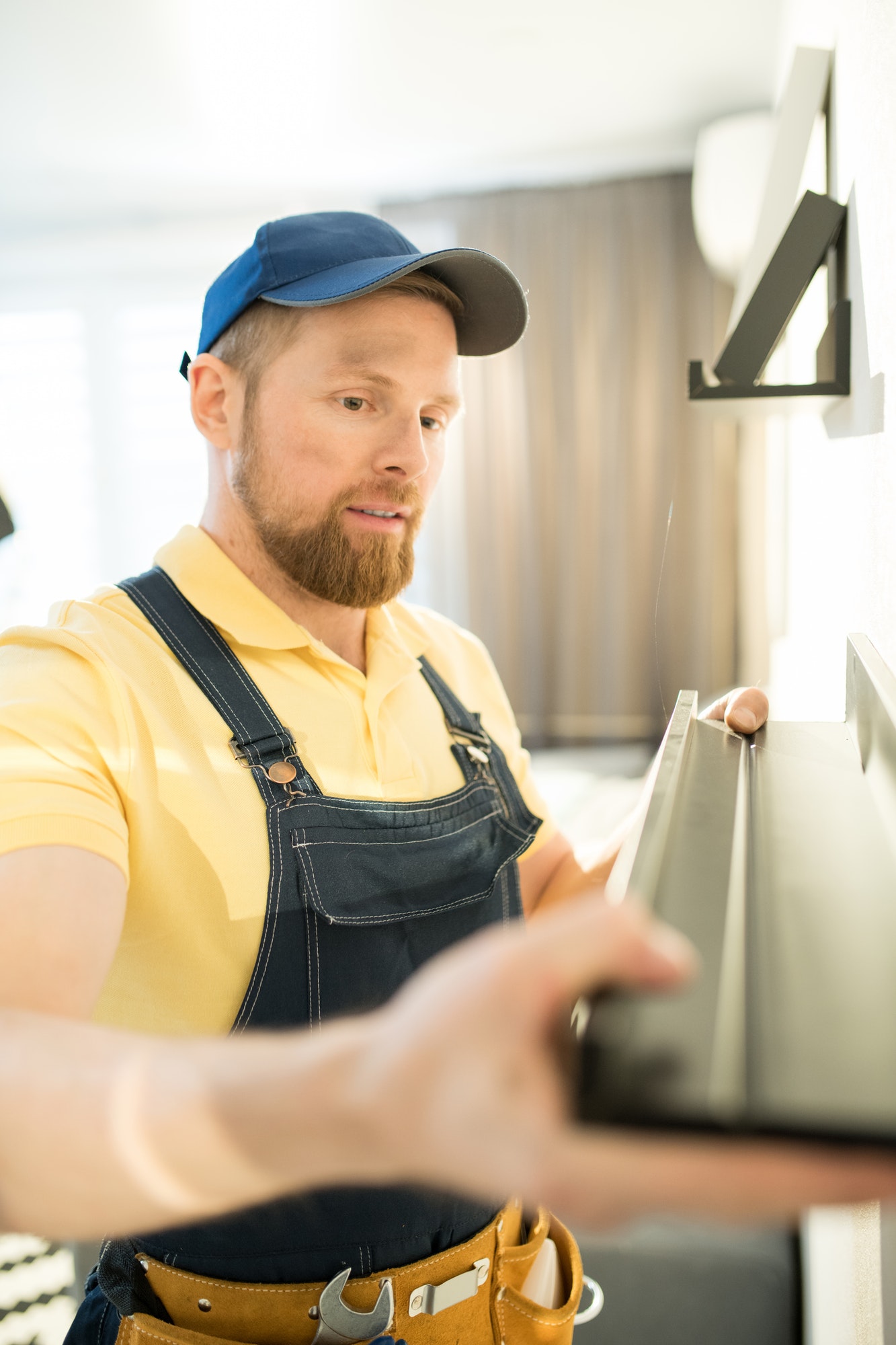 Young repairman hanging shelf on wall